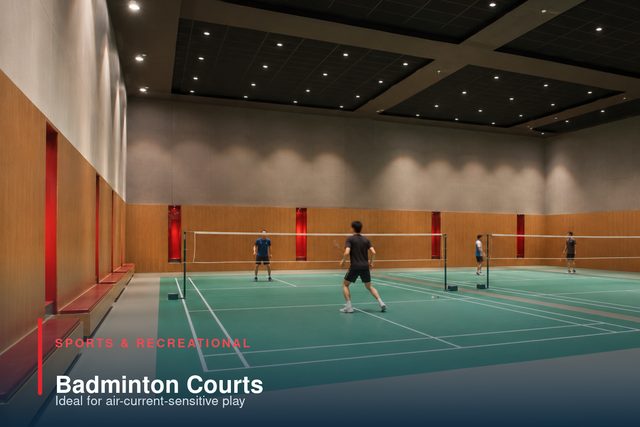 Two badminton courts in a timber-lined hall, with players mid-rally.