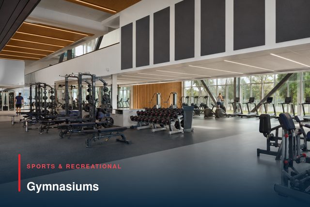 A gym floor with weights racks, benches and cardio machines along a fully glazed elevation.