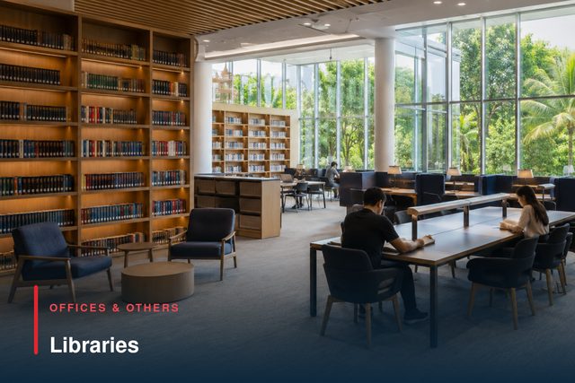 A library reading room with full-height bookshelves and long study tables.